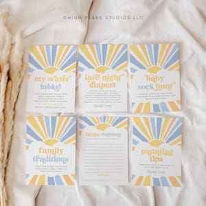 Peut inclure: Un ensemble de six cartes de jeu de baby shower imprimables avec un design rétro en forme de soleil éclatant en jaune, bleu et blanc. Les cartes présentent des textes tels que "My Water Broke", "Late Night Diapers", "Baby Sock Hunt", "Family Traditions" et "Parenting Tips".