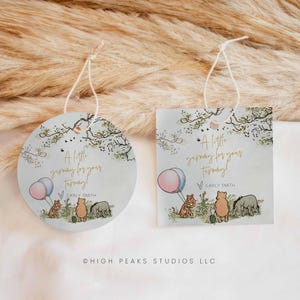 Könnte beinhalten: Zwei hellblaue Geschenkanhänger, einer rund und einer quadratisch, mit Winnie Puuh-Motiv. Jeder Anhänger zeigt den Text "A little yummy for your tummy!" und Illustrationen von Puuh, Tiger und Ferkel. Inklusive einer Schnur zum Aufhängen.
