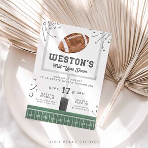 May include: A green and white football-themed invitation for a first birthday party. The invitation features a watercolor illustration of a football, a football field, and the text "Weston's First Year Down". The invitation also includes the date, time, and location of the party.