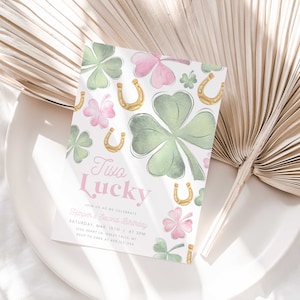 May include: A green and pink invitation card with a watercolor design of shamrocks and gold horseshoes. The text reads "Two Lucky" and "Harper's Second Birthday".