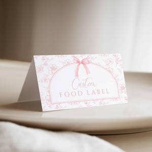 May include: A white card with a pink floral pattern and a pink ribbon bow. The card has a white oval with the text "Custom Food Label" in pink.