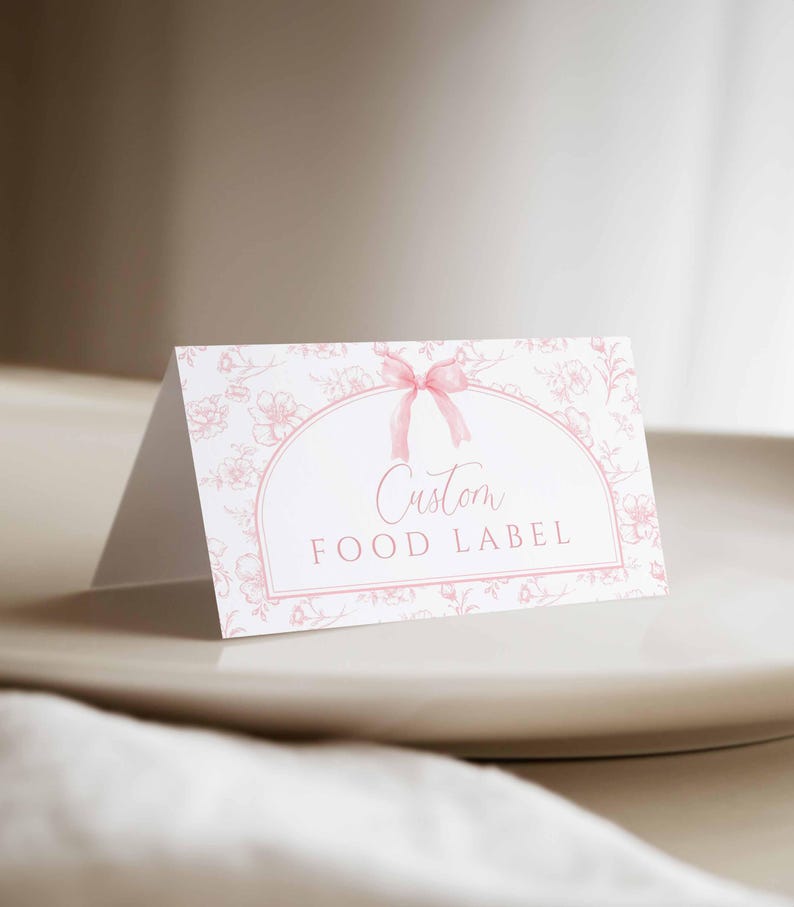 May include: A white card with a pink floral pattern and a pink ribbon bow. The card has a white oval with the text "Custom Food Label" in pink.