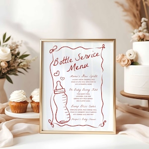 May include: A framed sign with a gold border displays a "Bottle Service Menu" in red script. The menu lists drink recipes like "Mama's Blow Spritz" and "Oh Baby Berry Fizz", with a baby bottle illustration. The sign is for "Harper's Baby Shower".
