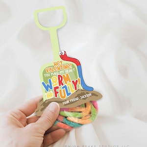 May include: A Valentine's Day card with a worm and fuzzy theme. The card features a cartoon worm and the text "Hey Valentine! You make my heart worm and fully!" The card is held by a hand.