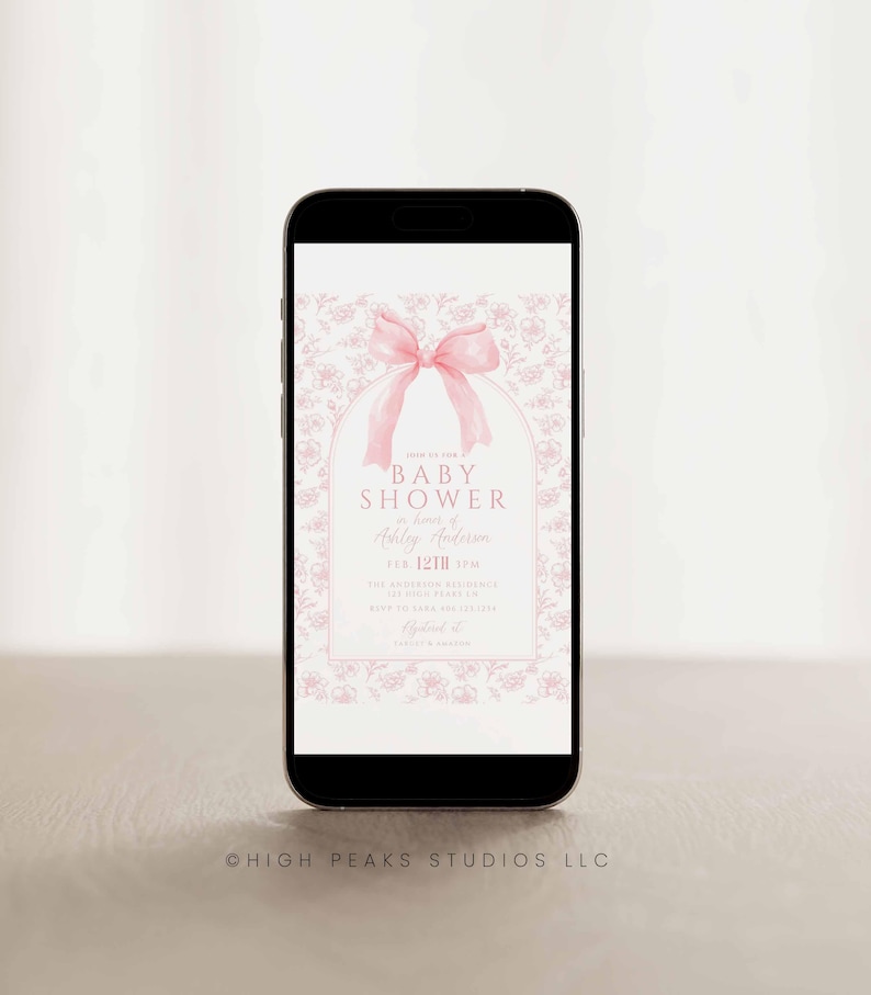 May include: A pink and white baby shower invitation on a smartphone screen. The invitation features a pink bow and a floral pattern. The text reads "Baby Shower" in honor of "Ashley Anderson" on "Feb 12th 3PM".