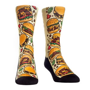 May include: A pair of colorful socks with a pattern of cartoon burgers on a light yellow background. The socks are black at the toes and heels.