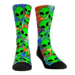 May include: A pair of colorful socks with a tie-dye pattern and green alien faces. The socks are black at the toes and heels.