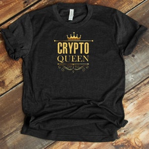 Puede incluir: Una camiseta gris oscuro con una corona dorada, las palabras "CRYPTO QUEEN" y un adorno floral.