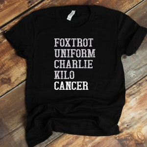May include: Black t-shirt with white text that reads "FOXTROT UNIFORM CHARLIE KILO CANCER"