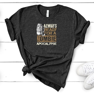 May include: A dark grey t-shirt with a distressed graphic of a backpack and the text "Always Ready For A Zombie Apocalypse".