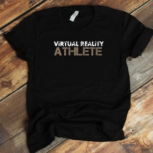Może przedstawiać: Czarny T-shirt z napisem "VIRTUAL REALITY ATHLETE" w białych i brązowych literach.