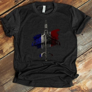 May include: A dark gray t-shirt with a distressed French flag design featuring a fighter jet in the center.