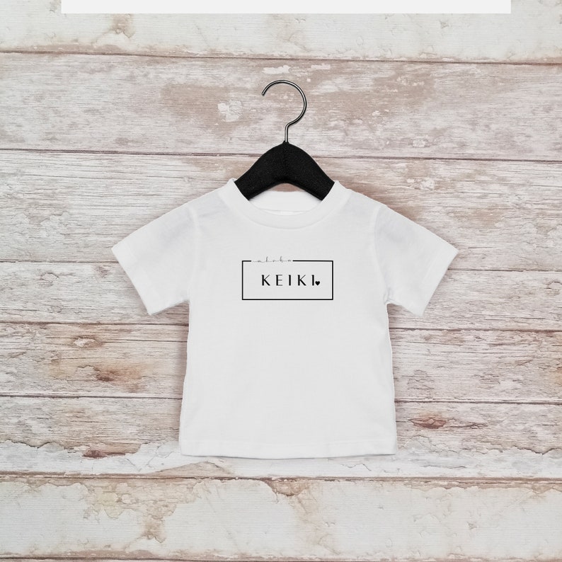 May include: White t-shirt with a black box and the text "aloha KEIKI" with a small heart.