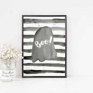 May include: Black and white watercolor print of a ghost with the word "boo!" on a striped background. The print is framed in a black frame.