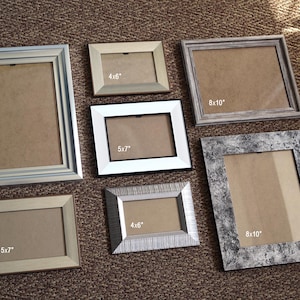 May include: A selection of picture frames in various sizes and styles. Frames include sizes 10x15 cm, 13x18 cm, and 20x25 cm, as well as an A4 frame. The frames are in silver, white, and neutral tones.