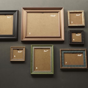 May include: A collection of seven picture frames in various colours and sizes, including a black 5x7 inch frame, a copper 10x8 inch frame, a silver 4x4 inch frame, a dark 3x3 inch frame, a bronze 3x3 inch frame, a green 5x7 inch frame, and a blue 4x6 inch frame.