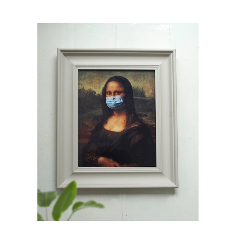 Puede incluir: Una impresi&oacute;n enmarcada de la Mona Lisa, con el sujeto usando una m&aacute;scara quir&uacute;rgica azul.