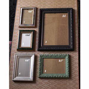 May include: A selection of five picture frames in different styles and sizes. Frames are gold, green, silver, and black. Sizes include 4x6 inches, 3.5x5 inches, and 5x7 inches. One frame is labeled A4.
