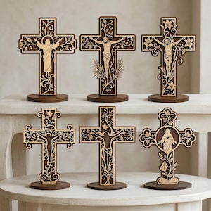 May include: Six standing wooden crosses featuring intricate laser-cut designs. Each cross displays a unique religious figure or scene, including depictions of Jesus and floral motifs, all mounted on circular wooden bases with a two-tone finish.