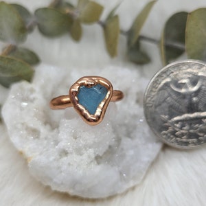 K&ouml;nnte beinhalten: Ein Kupferring mit einem hellblauen Aquamarin-Stein, der in der Mitte eingesetzt ist. Der Ring ist handgefertigt und hat einen rustikalen, organischen Look.