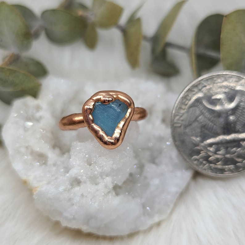 K&ouml;nnte beinhalten: Ein Kupferring mit einem hellblauen Aquamarin-Stein, der in der Mitte eingesetzt ist. Der Ring ist handgefertigt und hat einen rustikalen, organischen Look.