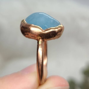 Op de afbeelding: Een ring met een lichtblauwe aquamarijn steen gezet in een koperen band.