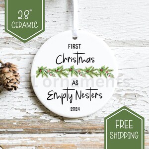 Peut inclure: Ornement de Noël en céramique blanche, 7,1 cm de diamètre, avec le texte "First Christmas as Empty Nesters 2024". L'ornement présente un motif de guirlande de houx vert et rouge et un ruban blanc pour l'accrocher.