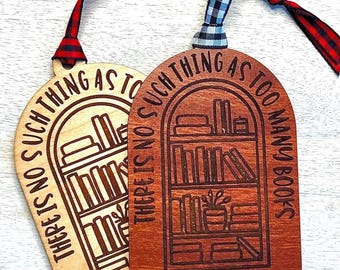 May include: Two wooden bookmarks with the phrase "THERE IS NO SUCH THING AS TOO MANY BOOKS" engraved. One is light wood, the other is stained brown. Each has a ribbon for hanging, one red plaid, the other black and white.