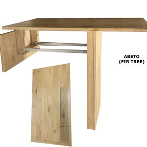 Pu&ograve; includere: Un tavolo in legno chiaro con piano rettangolare e una singola gamba di supporto verticale. Il tavolo presenta un meccanismo di chiusura con binari in metallo argentato e un pannello laterale incernierato. Il testo ABETO (FIR TREE) &egrave; a destra.