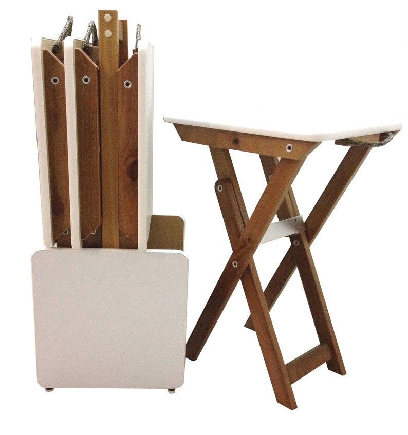 Puede incluir: Un juego de cuatro mesas plegables blancas con patas de madera. Las mesas est&aacute;n apiladas y plegadas, con las patas metidas. Las mesas est&aacute;n hechas de madera y tienen un acabado blanco.