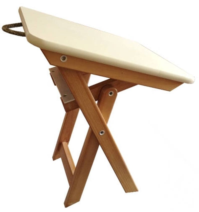 Puede incluir: Una mesa plegable blanca con un marco de madera. La mesa tiene un asa de cuerda y est&aacute; hecha de madera natural.