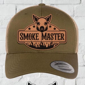 Puede incluir: Gorra de camionero marrón con un logotipo de cerdo que dice "SMOKE MASTER". Debajo, se muestra un gráfico en blanco y negro del mismo logotipo. Las palabras "INSTANT DIGITAL DOWNLOAD" están en la parte inferior.