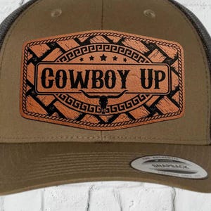 May include: A brown and black trucker hat with a leather patch that reads "COWBOY UP". The patch has a rope border design and a bull skull graphic. The hat is a digital download.