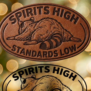 Puede incluir: Dos diseños ovalados con una ilustración de mapache y el texto "SPIRITS HIGH STANDARDS LOW". Uno es marrón y texturizado, el otro en blanco y negro. La imagen también muestra "4 Designs Included" y opciones de formato de archivo.