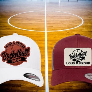May include: Two baseball caps, one white and one burgundy, with a black and white basketball graphic and the text "Loud & Proud Basketball Mom".