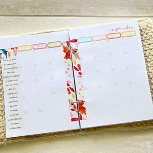 Könnte beinhalten: Geöffneter Planer mit einem September-Kalender. Die weißen Seiten haben ein Raster für jeden Tag. Dekoratives Klebeband mit Herbstblättern und Sternen verziert die Bindung. Die Wochentage sind in farbigen Kästchen.