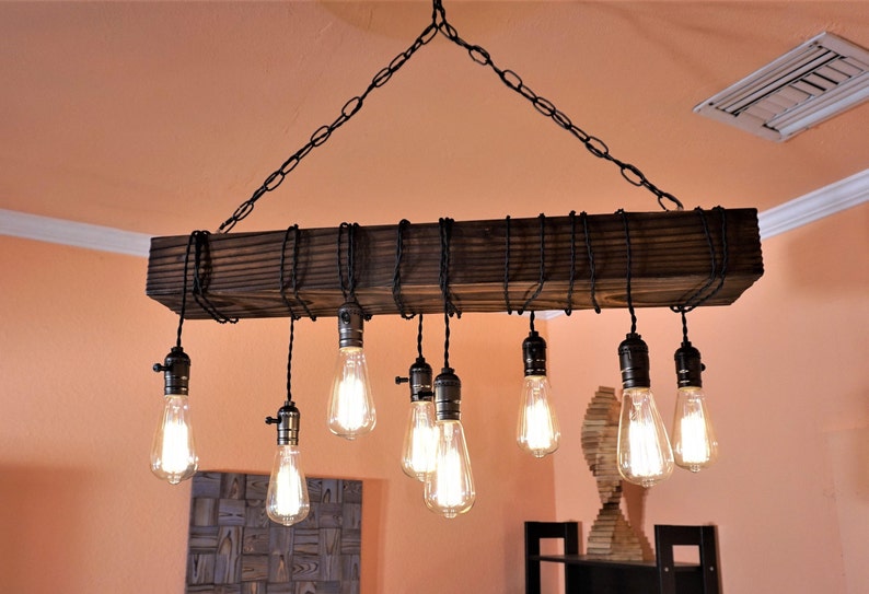 May include: A rustic wooden chandelier with a black chain and 9 exposed Edison bulbs. The chandelier is made of reclaimed wood and has a natural finish.