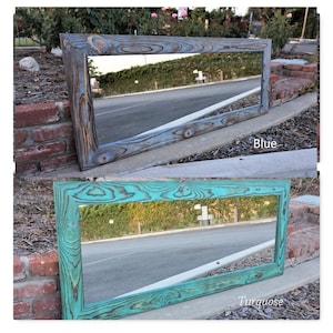 May include: Rectangular wooden framed mirror in two colors: blue and turquoise. The wood grain is visible, adding texture. The mirror is leaning against a brick wall and concrete surface. The word "Blue" is written on the image.