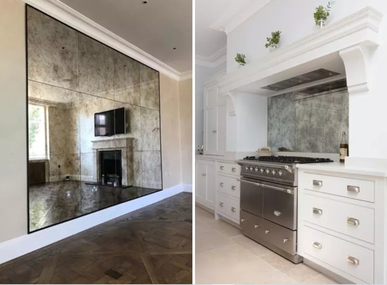 May include: A large wall-mounted antique-style mirror with a distressed, mottled finish composed of multiple rectangular panels. The mirror reflects a room with a fireplace and television, and a kitchen with a stainless steel range and white cabinets.