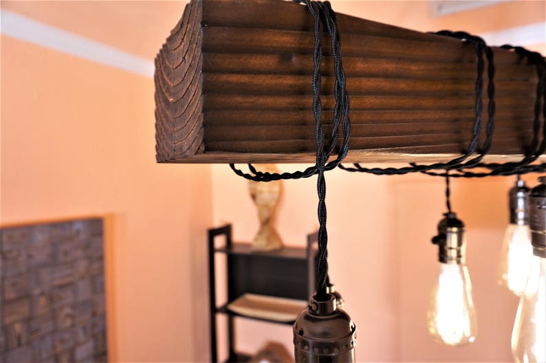 May include: A rustic wooden ceiling light fixture with black electrical cords and exposed Edison bulb sockets.
