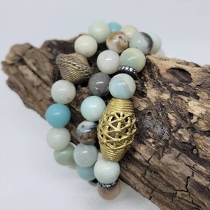 May include: Three layered bracelets with blue, green, and brown beads. The bracelets feature gold and silver accents.
