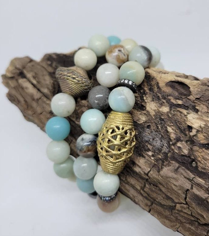 May include: Three layered bracelets with blue, green, and brown beads. The bracelets feature gold and silver accents.