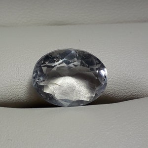 May include: A clear oval-shaped gemstone with a faceted cut.