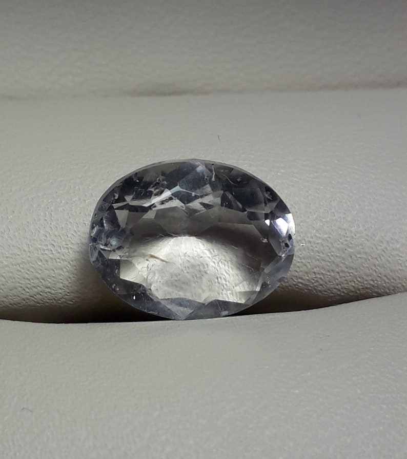 May include: A clear oval-shaped gemstone with a faceted cut.