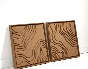 May include: Two framed wall art pieces with a topographic map design. The artwork features a series of layered, curved lines carved into a light brown surface, creating a 3D effect. The frames are also light brown.