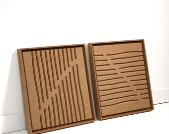 May include: Two square, wooden wall art pieces. One features vertical and angled grooves, the other has horizontal and curved grooves. Both are framed in a light brown color and rest against a white wall.