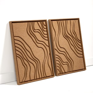 May include: Two rectangular, brown wall art panels with a topographic design. Each panel features a series of carved, flowing lines, creating a layered effect. The panels are displayed against a white wall.