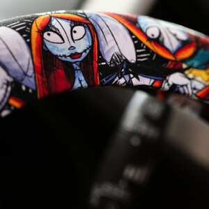 Puede incluir: Una funda para volante negra con un estampado colorido que presenta personajes de la pel&iacute;cula Pesadilla antes de Navidad. Los personajes incluyen a Jack Skellington, Sally y Oogie Boogie.