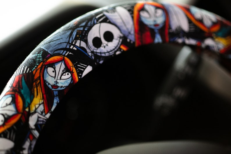 Puede incluir: Una funda para volante negra con un estampado colorido de personajes de la pel&iacute;cula Pesadilla antes de Navidad. Los personajes incluyen a Jack Skellington, Sally y Oogie Boogie.