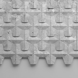 Może przedstawiać: Szary, teksturowany, geometryczny panel ścienny z powtarzającym się wzorem w kształcie litery T. Panel ma szorstki, kamienny wygląd i jest zamontowany na białej ścianie. Projekt jest nowoczesny i minimalistyczny.